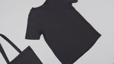 close up of black bag and t-shirt on white background, with copy space, slow motion