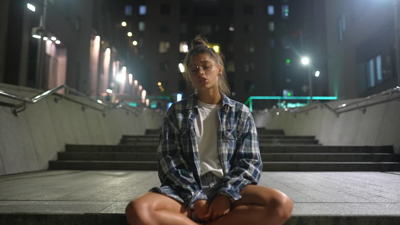 mujer sentada en las escaleras de la ciudad por la noche