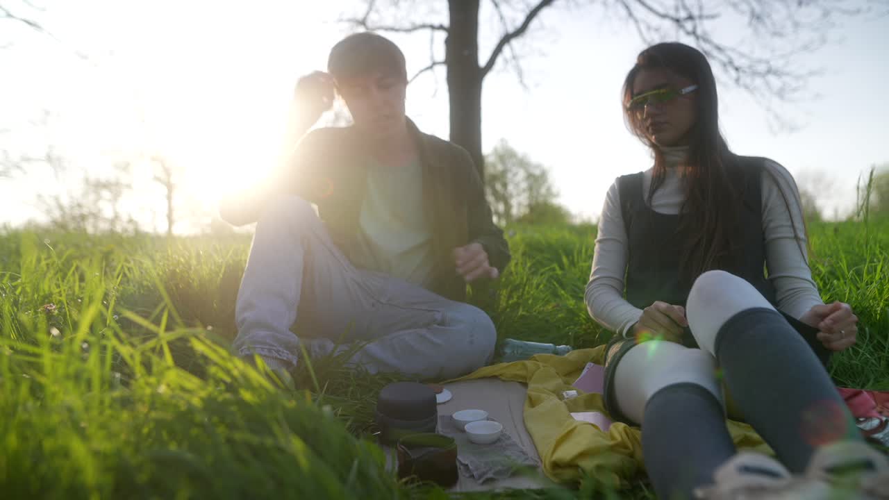 Couple enjoying a tea picnic in the park at sunset