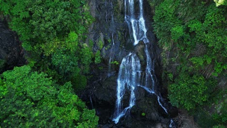 a close-up aerial shot starts near a swirling waterfall, then slowly pulls away and rises, revealing the full falls and lush nature at balagbag falls, real, quezon