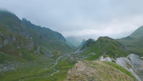 Adelantando-El-Acantilado-Al-Valle-Brumoso-Con-Un-Pequeño-Río-En-La-Montaña,-Alpes-Franceses