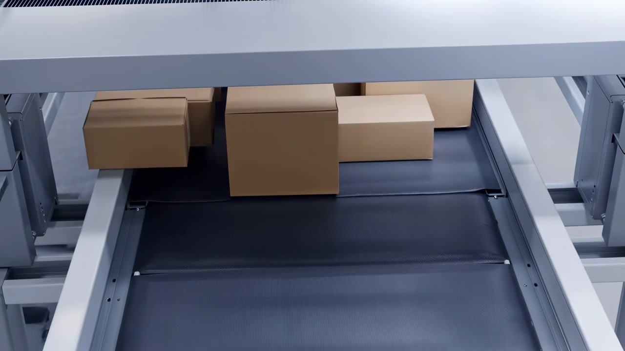 Cluster of sealed cardboard boxes moving along dark textured conveyor belt inside industrial packaging machine, showing automated handling, sorting, and transit in cool controlled light