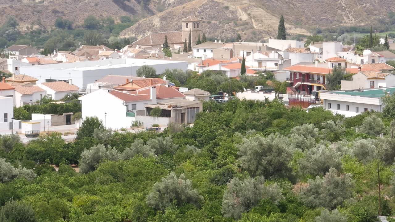 View of Melegís with its white houses surrounded by lush orange and olive groves. Andalusian rural architecture in the heart of the Lecrín Valley, Granada