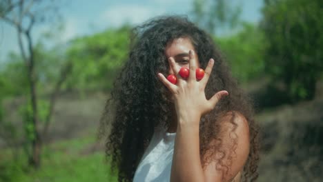 close-up of a woman holding tomatoes between her fingers, then releasing them as they fall from her open hand