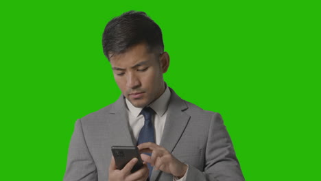retrato de un hombre de negocios serio en traje contra mensajes de pantalla verde en el teléfono móvil 1