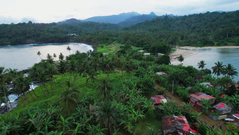 aerial view low over ramshackle dwellings and a dirt road, in agua izé, sao tome