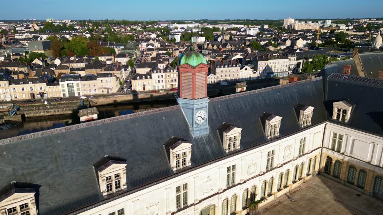 A drone pullback shot reveals Château Neuf in Laval, showing the courtyard, the historic building, and the city across the Mayenne river