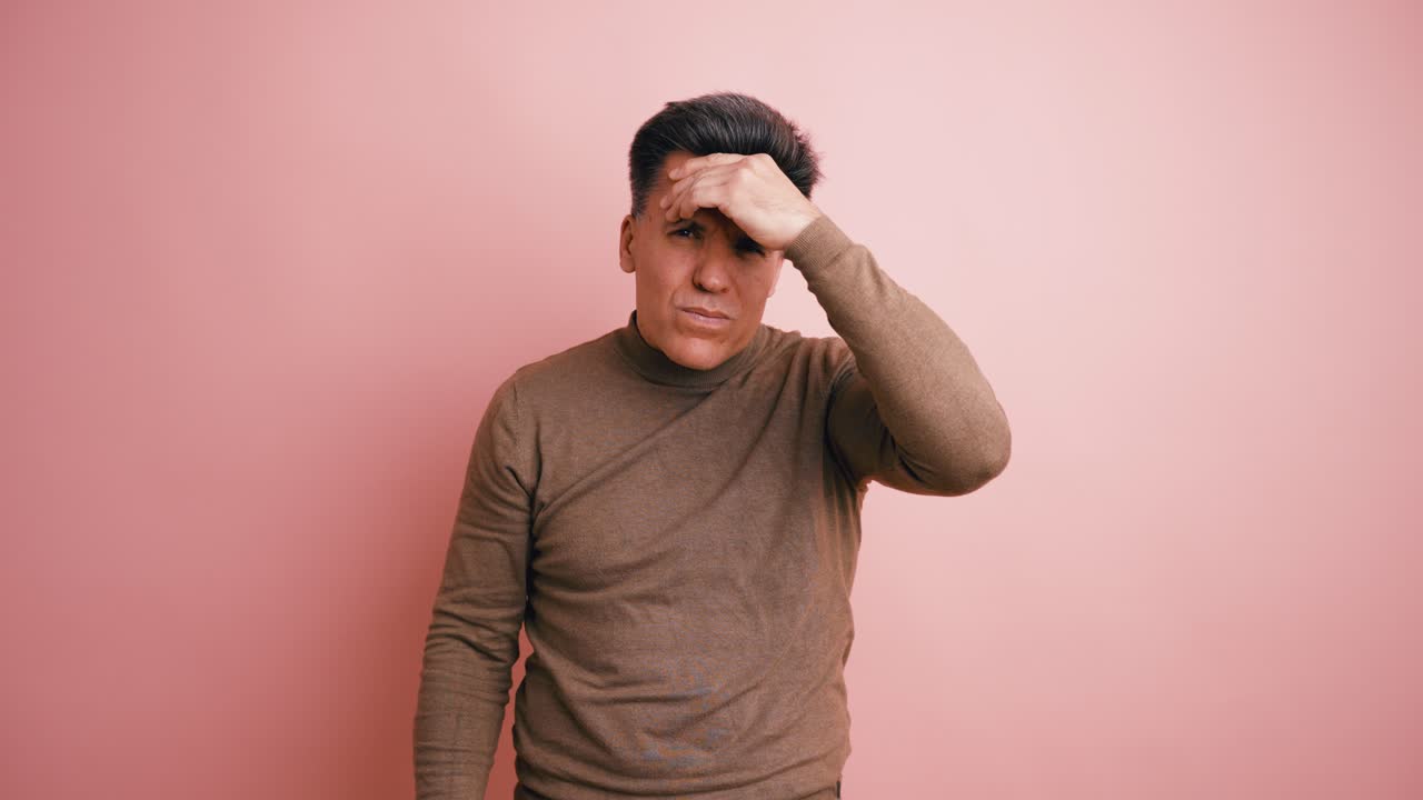 Man Holding Head in Pain Against Pink Background