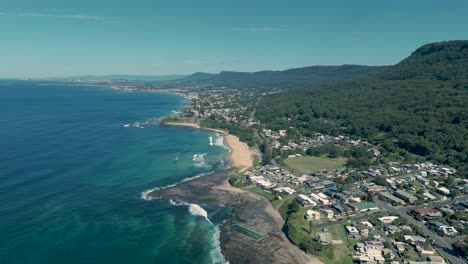 aerial trucking pan of coledale, australia, featuring the coastline, lush green hills, and the vast ocean on a clear day