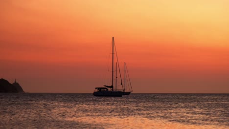 silhouette of a sailboat at sunset on calm seas, with warm orange skies and a distant headland. evokes tranquility, freedom, and adventure—ideal for travel and exploration themes.