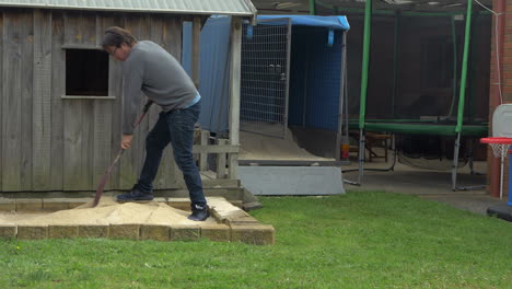 man spreading out sand in a childs sandpit