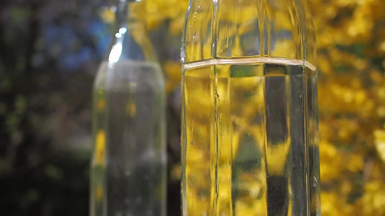 Glass bottle with fresh water on yellow, floral background