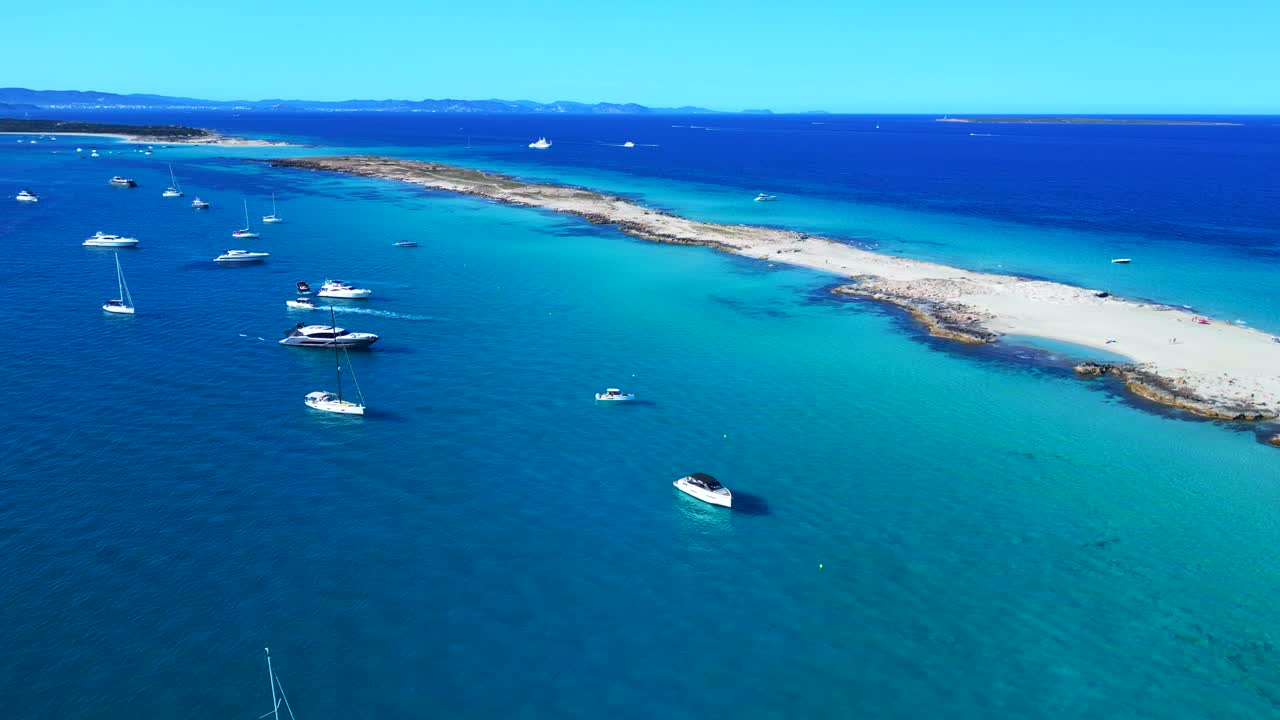 Formentera island coastline with clear turquoise blue water and anchored boats under a blue sky. Spectacular aerial view panorama overview drone