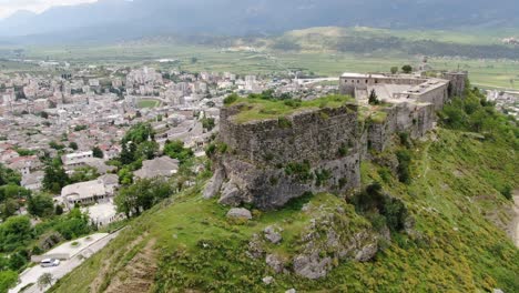 drone view in albania flying in gjirokaster town over a medieval castle on high ground fort showing the brick brown roof houses