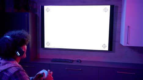 playing video game, man using game controller and wearing headphones in living room, copy space