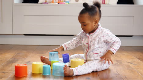 female toddler at home playing with stacking plastic toy