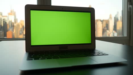 portátil de negocios con pantalla verde monitor de clave croma y fondo de paisaje urbano.