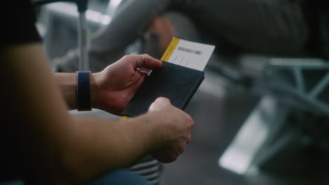 man holding passport and boarding pass at airport