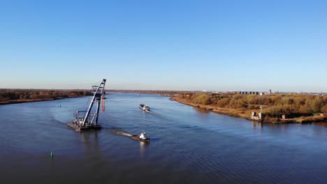 Tugboat-Towing-Bulk-Carrier-Loaded-With-Heavy-Equipment-Across-The-River-In-Barendrecht,-Netherlands