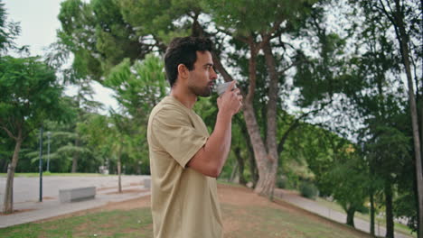 resting tourist drinking coffee takeaway in beautiful green town garden close up