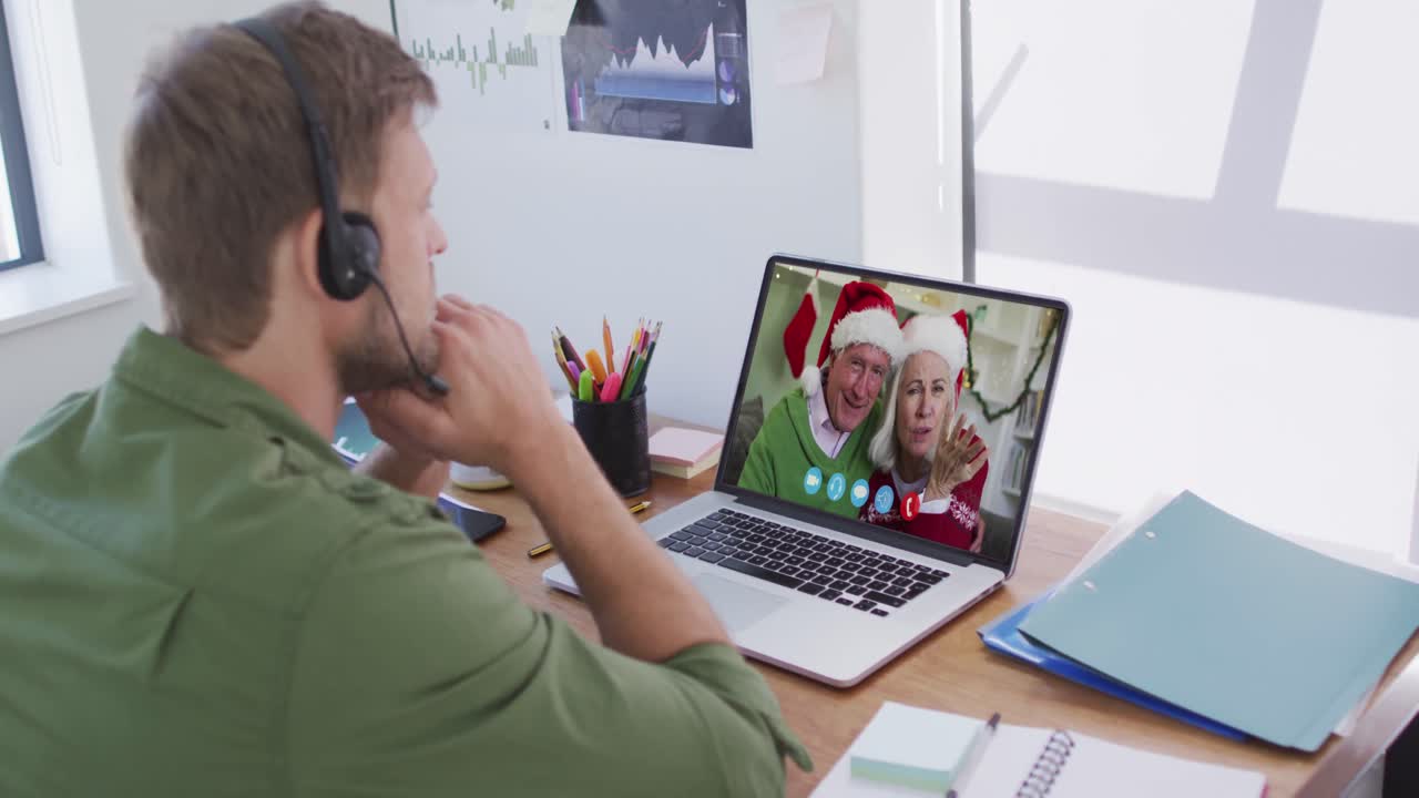 hombre caucásico que usa auriculares de teléfono en la computadora portátil video chat durante la navidad en casa