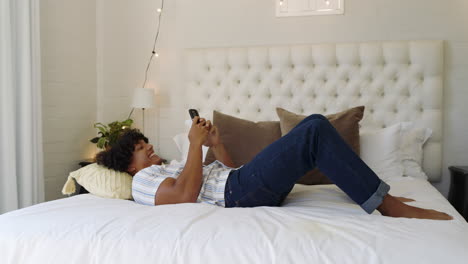 relaxing at home, man lying on bed using smartphone, enjoying leisure time