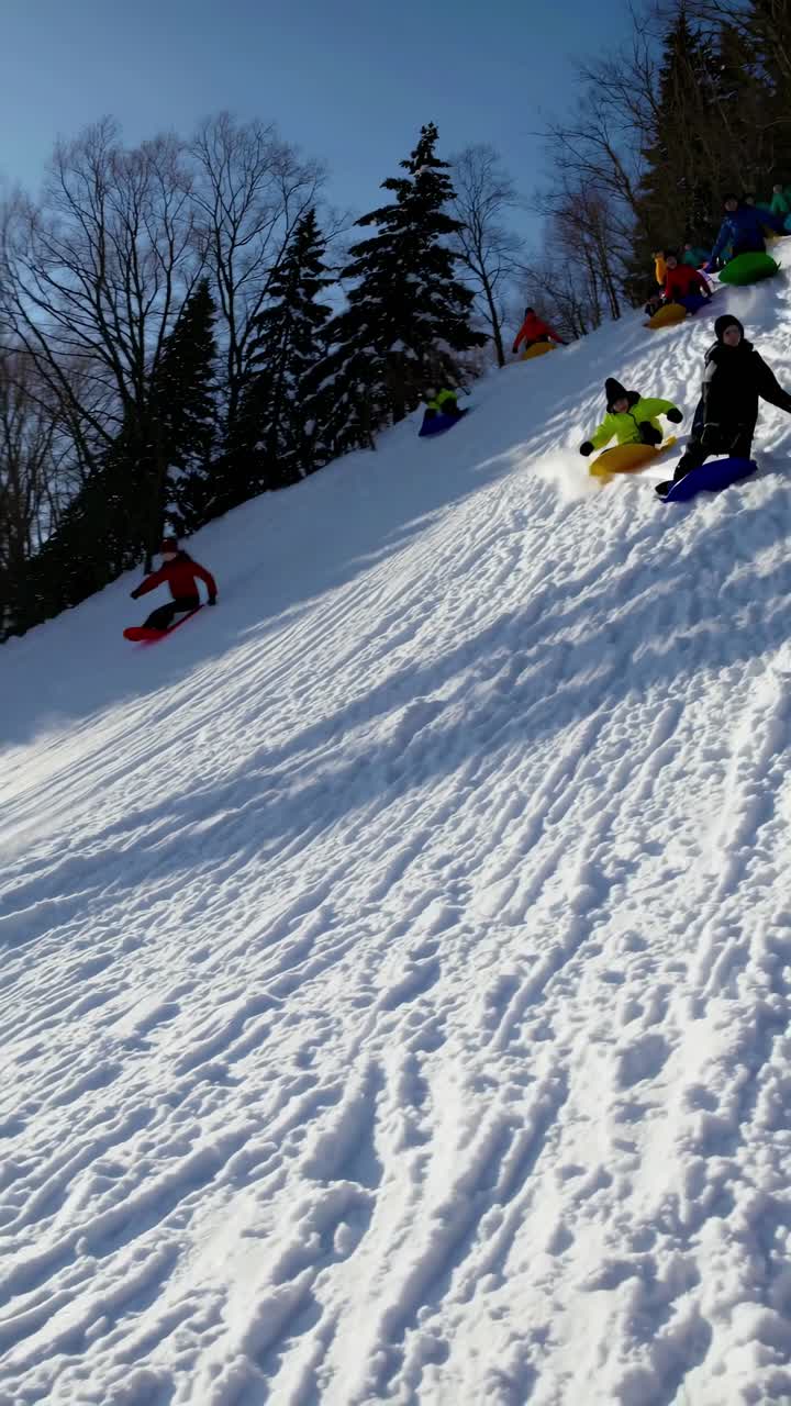 Video captures a dynamic low-angle view of children sledding down a snowy hill