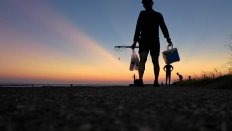 silhouette of fisherman with rod walking after fishing in pacific ocean in asia