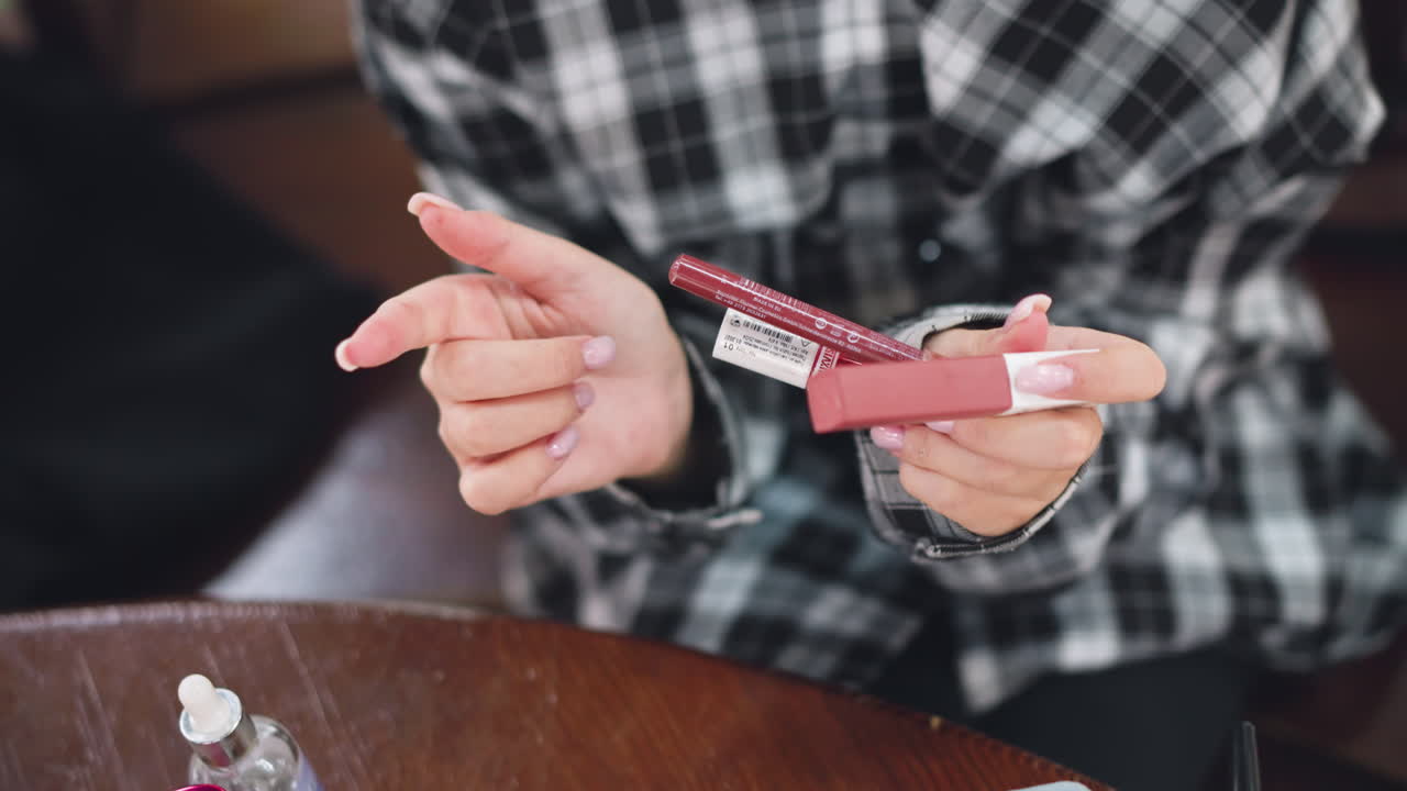 손으로 다양한 화장품을 검토하고 어떤 제품을 사용해야 하는지 결정하려고 노력하는 여성의 부분적 인 시각, 그녀의 끔하게 매니큐어 된 손과 세련된 의상은 아름다움과 개인 관리 선택을 강조합니다.