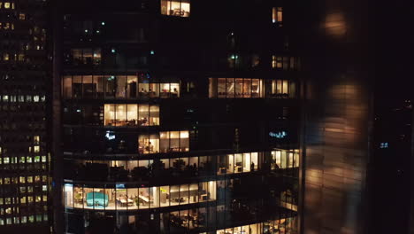 Descending-shot-of-modern-high-rise-building-at-night.-Lighted-office-windows-in-late-evening.-Warsaw,-Poland