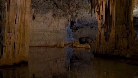 reflejo del agua en la enorme cueva de neptuno de piedra caliza con estalagmitas y estalactitas tropfsteinhöhle grotta di nettuno en cerdeña, italia