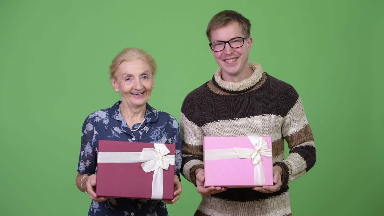 Happy grandmother and grandson holding gift box together