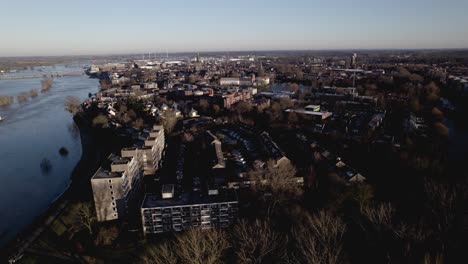 Niederländische-Stadt-In-Flacher-Landschaft-Mit-Großem-Fluss-Ijssel,-Der-Vorbeiführt-Und-Ein-Binnenfrachtschiff-Zeigt