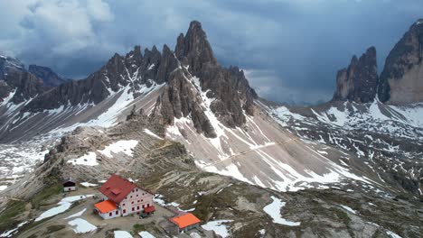 Toma-Aérea-Panorámica-De-Una-Montaña-Puntiaguda-Con-Refugio-Locatelli.