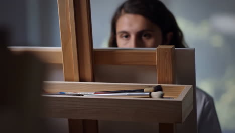 artist with paintbrushes on easel