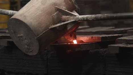 pouring incandescent liquid iron into a mold from a bucket