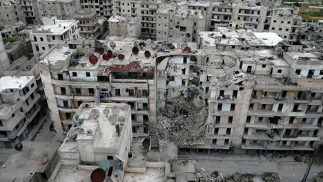 aerial view over roofs of buildings in aleppo, syria. there is antenna rusted with time on the rooftop, the buildings are in ruins 4k