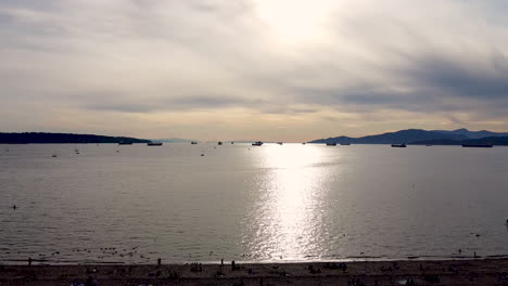 Vuelo-Aéreo-De-La-Puesta-De-Sol-De-Verano-Sobre-Una-Playa-Privada-Residencial-En-Un-Puerto-Industrial-Comercial-Con-Barcazas-De-Carga,-Barcos-De-Carga-Alineados-Para-El-Comercio-De-Exportación-De-Iport-Y-Embarcaciones-Recreativas-Estacionadas-2-2