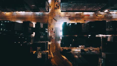 a top view of a street in a busy city during the night, some bus and traffic stop at the traffic light