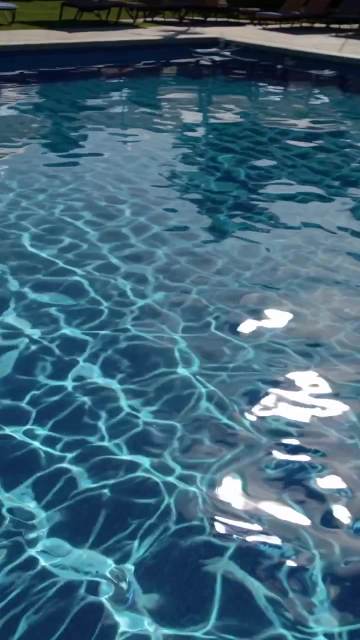 Krusende blåt vand i en swimmingpool på et tropisk resort