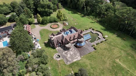 Aerial view circling neglected millionaire property with swimming pool and overgrown gardens