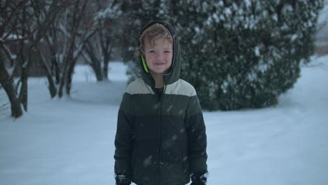 young happy boy smiling outside while playing in snow during winter