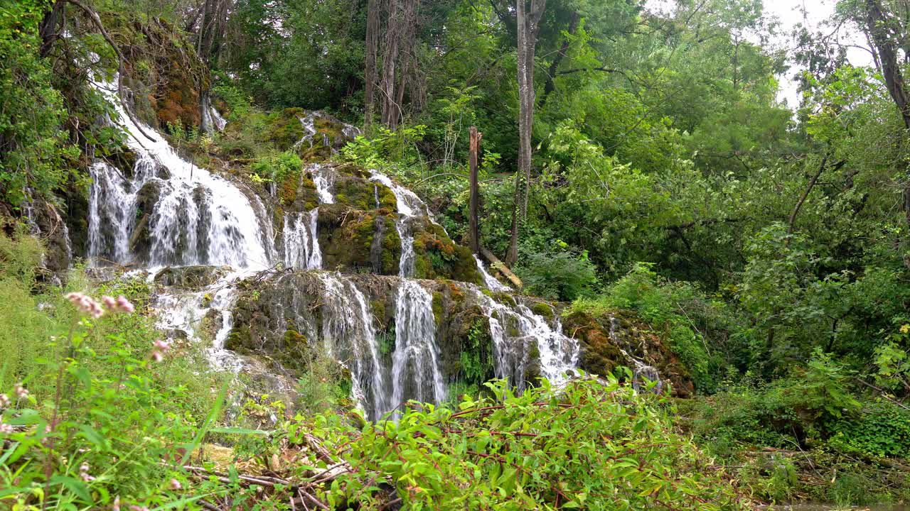 Diversi livelli di cascate d'acqua circondate da folti cespugli e alberi verdi nel Parco Nazionale di Krka in Croazia.