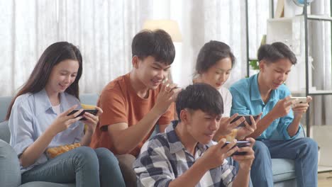 asian teenagers playing video games on smart phone and celebrating victory at home