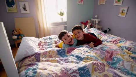 two young boys playfully wrestling and laughing on a bed