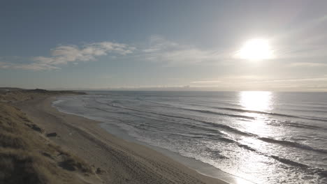 backwards flying drone shot over the dunes near borestranda norway during sunset going away from the beach and sea and flying upwards for an overview shot log