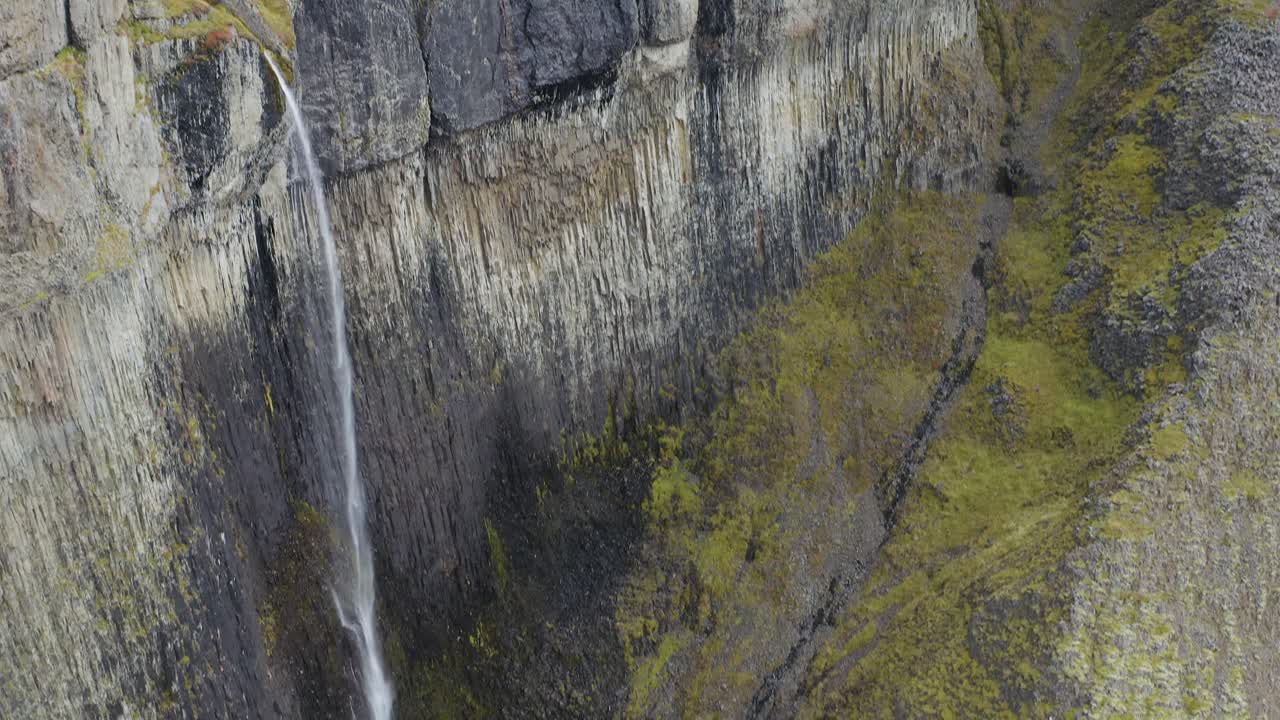 inclinación aérea hacia abajo de la caída de la cascada que se estrella en el valle durante el día soleado