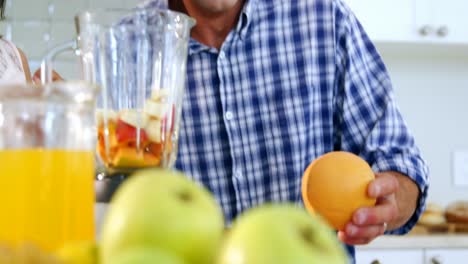 Father-and-daughter-preparing-smoothie-in-kitchen