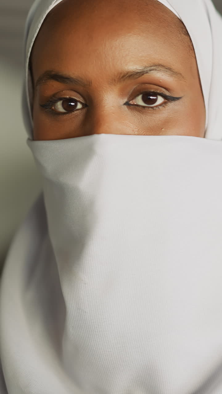 Attractive black Arabian woman hides face with national headscarf under bridge on waterfront slow motion. Muslim female accessory in everyday life