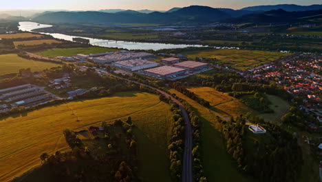flying over the picturesque countryside on the golden hour. approaching the territory of the plant located near the river in rural area. slovakia industry